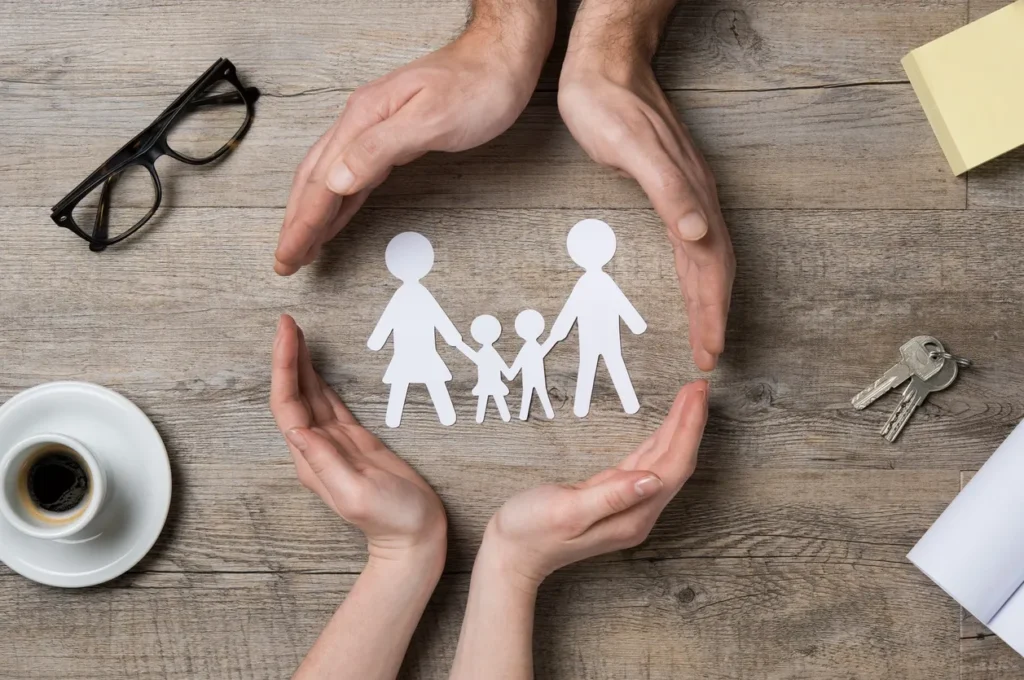 A paper cut out of a family with hands around it.