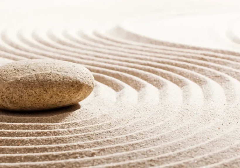 A rock sitting on top of sand in the middle of a circle.