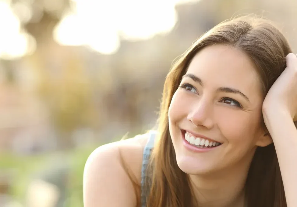A woman smiling with her teeth looking to the side.