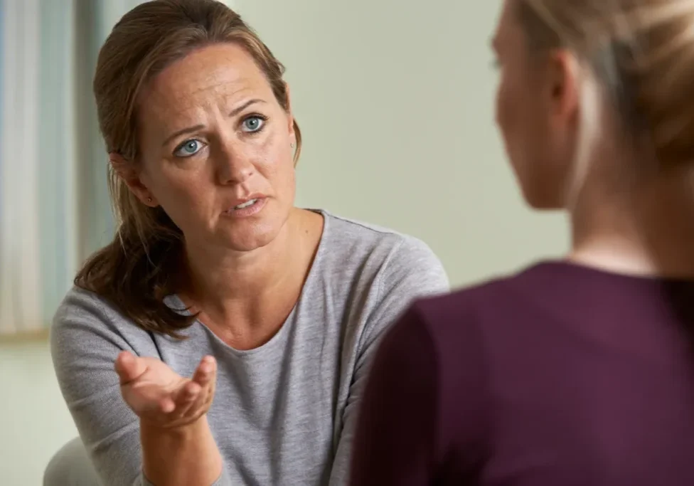 A woman talking to another person in front of a mirror.