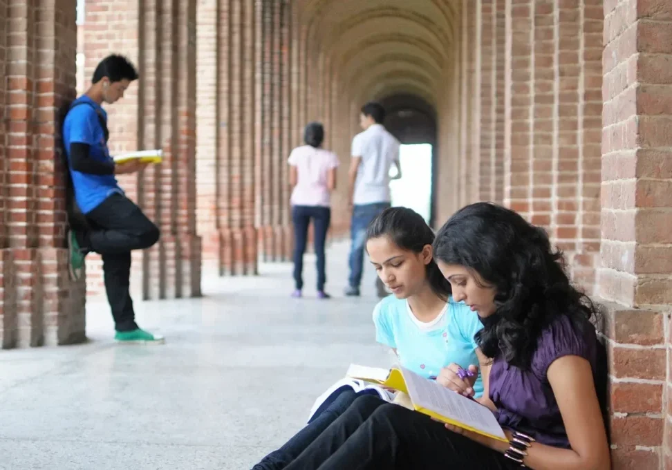 Two students are sitting on the ground reading.